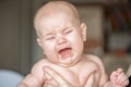 Portrait of a crying baby on a green bed in the bedroom. Child`s emotions Royalty Free Stock Photo