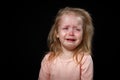 Portrait of a crying blond baby girl on black background Royalty Free Stock Photo