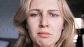 Portrait of crying grieving woman of 30 years. Grimace of sadness with tears in her eyes and crooked chin of blonde