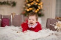 Portrait of crying little girl in red knitted sweater with Christmas present box near Christmas tree Royalty Free Stock Photo