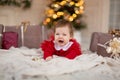 Portrait of crying little girl in red knitted sweater with Christmas present box near Christmas tree Royalty Free Stock Photo