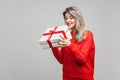 Portrait of curious beautiful blonde woman with red listick in bright casual sweater, isolated on gray background