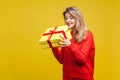 Portrait of curious beautiful blonde woman with red listick in bright casual sweater, isolated on yellow background