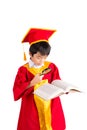 Portrait Of Curious Boy In Red Gown Kid Graduation With Mortarboard Looking A Book Through Magnifying Glass Royalty Free Stock Photo