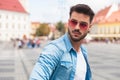 Portrait of curious casual man looking behind on urban background