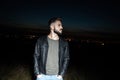 Portrait of curious man in leather jacket standing outside