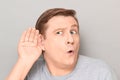 Portrait of curious man placing hand near ear and eavesdropping Royalty Free Stock Photo