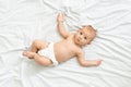 Portrait of curious newborn baby in diaper lying on bed