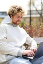 Portrait of a curly-haired student working on a laptop on campus