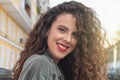 Portrait of curly-haired young woman on the street. Latin woman. Arab woman
