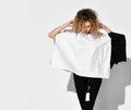 Portrait of curly woman in stylish clothes two-tone poncho blouse stands holding hands at head and looking down Royalty Free Stock Photo