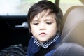 Portrait cut lilttle boy sitting in a car in safety chair, Adorable toddler boy sitting in car seat, Child in car seat looking dow