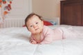 Cute adorable Asian mixed race smiling baby girl four months old lying on tummy on bed Royalty Free Stock Photo