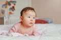 Cute adorable Asian mixed race smiling baby girl four months old lying on tummy on bed Royalty Free Stock Photo
