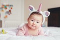 Cute adorable Asian mixed race smiling baby girl four months old lying on tummy on bed