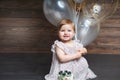 Portrait of cute adorable baby girl celebrating her first birthday with cake and balloons