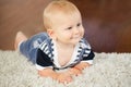 Portrait of cute adorable blond Caucasian smiling baby boy with blue eyes lying on floor in kids children room Royalty Free Stock Photo