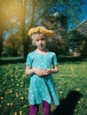 Portrait of cute adorable blonde Caucasian girl in dandelion chaplet. Pensive child with flower wreath on head. Innocent beautiful Royalty Free Stock Photo