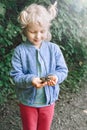 Portrait of cute adorable Caucasian blonde child girl holding small forest frog toad