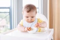 Caucasian child boy with dirty messy face sitting in high chair eating apple puree Royalty Free Stock Photo