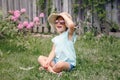 Portrait of cute adorable child girl in sunglasses and a straw hat sitting on grass outdoor. Happy smiling Caucasian kid having Royalty Free Stock Photo