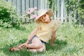 Portrait of cute adorable child girl in sunglasses and a straw hat sitting on grass outdoor. Happy smiling Caucasian kid having Royalty Free Stock Photo