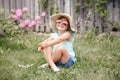 Portrait of cute adorable child girl in sunglasses and a straw hat sitting on grass outdoor. Happy smiling Caucasian kid having Royalty Free Stock Photo