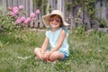 Portrait of cute adorable child girl in sunglasses and straw hat sitting on grass outdoor. Happy smiling Caucasian kid having fun Royalty Free Stock Photo