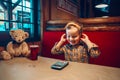 Portrait of cute adorable funny little boy toddler playing digital toy cell phone gadget with ear phones in a restaurant. Child Royalty Free Stock Photo