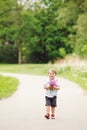 Portrait of a cute adorable funny little smiling boy toddler walking in park with lilac purple pink flowers in hands Royalty Free Stock Photo