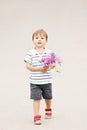 Portrait of a cute adorable funny little smiling boy toddler walking in park with lilac purple pink flowers in hands Royalty Free Stock Photo