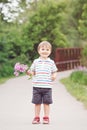 Portrait of a cute adorable funny little smiling boy toddler walking in park with lilac purple pink flowers in hands Royalty Free Stock Photo