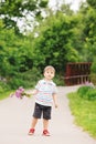 Portrait of a cute adorable funny little smiling boy toddler walking in park with lilac purple pink flowers in hands Royalty Free Stock Photo