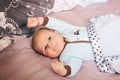 Portrait of cute adorable funny white Caucasian blond little baby boy newborn with blue grey eyes lying on large parents bed Royalty Free Stock Photo