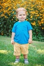 Portrait of cute adorable laughing smiling white Caucasian baby boy child standing among yellow flowers outside in garden park Royalty Free Stock Photo