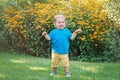 Portrait of cute adorable laughing smiling white Caucasian baby boy child standing among yellow flowers outside Royalty Free Stock Photo