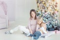 Portrait of cute adorable little blond children with mother enjoy sitting near christmas tree in cozy living room at home . Happy Royalty Free Stock Photo