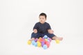 Portrait of cute adorable little boy is sitting and playing colorful balls on white background studio Royalty Free Stock Photo