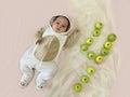 Portrait of a cute adorable smiling four month old baby boy lying on a bed with green apples Royalty Free Stock Photo