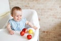 Portrait of cute adorable smiling laughing Caucasian child kid girl sitting in high chair eating apple fruit Royalty Free Stock Photo