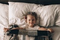 Portrait of cute adorable smiling little girl waking up and stretching in her bed Royalty Free Stock Photo