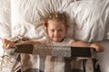 Portrait of cute adorable smiling little girl waking up and stretching in her bed Royalty Free Stock Photo