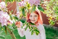 Portrait of a cute adorable smiling toothless little girl with red toned hair near blooming bush with rhododendron Royalty Free Stock Photo