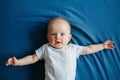 Cute adorable smiling white Caucasian baby girl boy with blue eyes four months old lying on bed in bedroom looking at camera Royalty Free Stock Photo