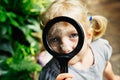 Caucasian girl looking at plants flowers anthurium through magnifying glass Royalty Free Stock Photo