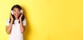 Portrait of cute african-american girl, smiling while listening to music in headphones, looking aside happy, standing Royalty Free Stock Photo