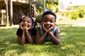 Portrait of cute african american siblings with hands on chins lying on grassy field in park Royalty Free Stock Photo