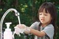 Portrait cute Asian girl aged 4 to 8 years old, washing her hands with soap from the tap. To clean her hands Frequent hand washing Royalty Free Stock Photo