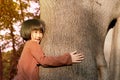 Portrait of a cute asian little girl hugging big tree. Royalty Free Stock Photo