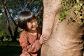 Portrait of a cute asian little girl hugging big tree. Royalty Free Stock Photo